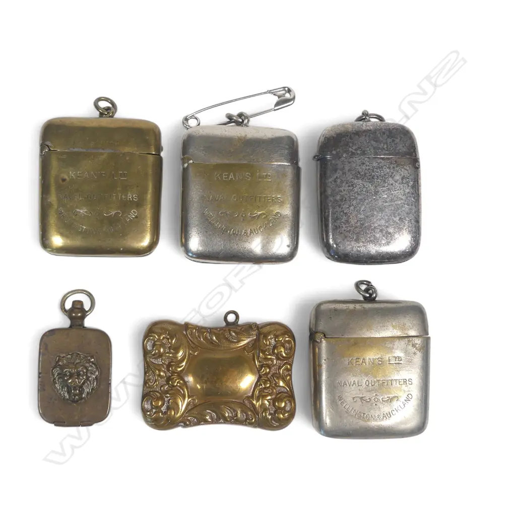 Five silver plate and brass vesta cases (three advertising Kean's Naval Outfitters Wellington & Auckland) and a small pill box with lion's head relief decoration. Image 1++