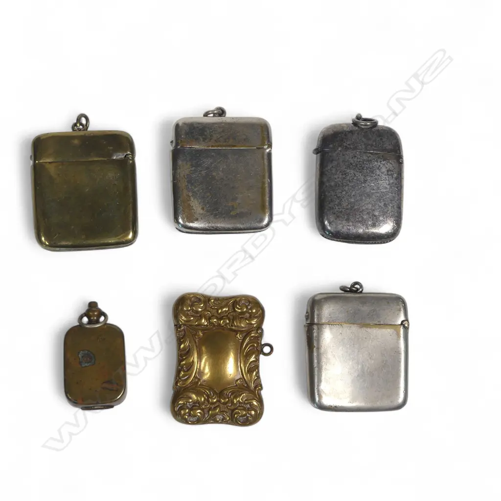 Five silver plate and brass vesta cases (three advertising Kean's Naval Outfitters Wellington & Auckland) and a small pill box with lion's head relief decoration. Image 1++