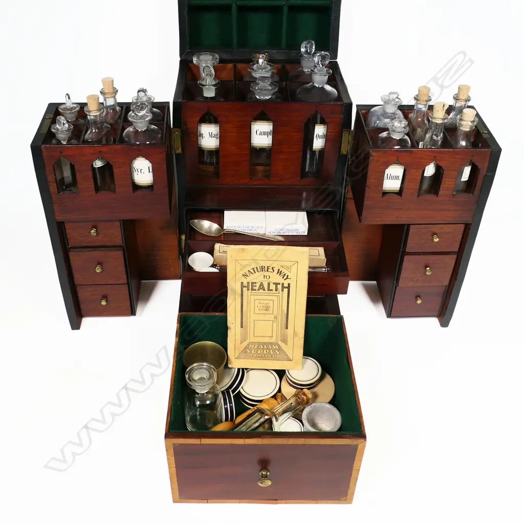 A George III period mahogany apothecary box, of tall oblong form with satinwood clashing and corners to the hinged lid, fitted with a stirrup handle. The front opening wing doors revealing an interior of 18 compartments and glass bottles, the front partitions pierced with Gothic openings to reveal the bottle labels, Image 1++