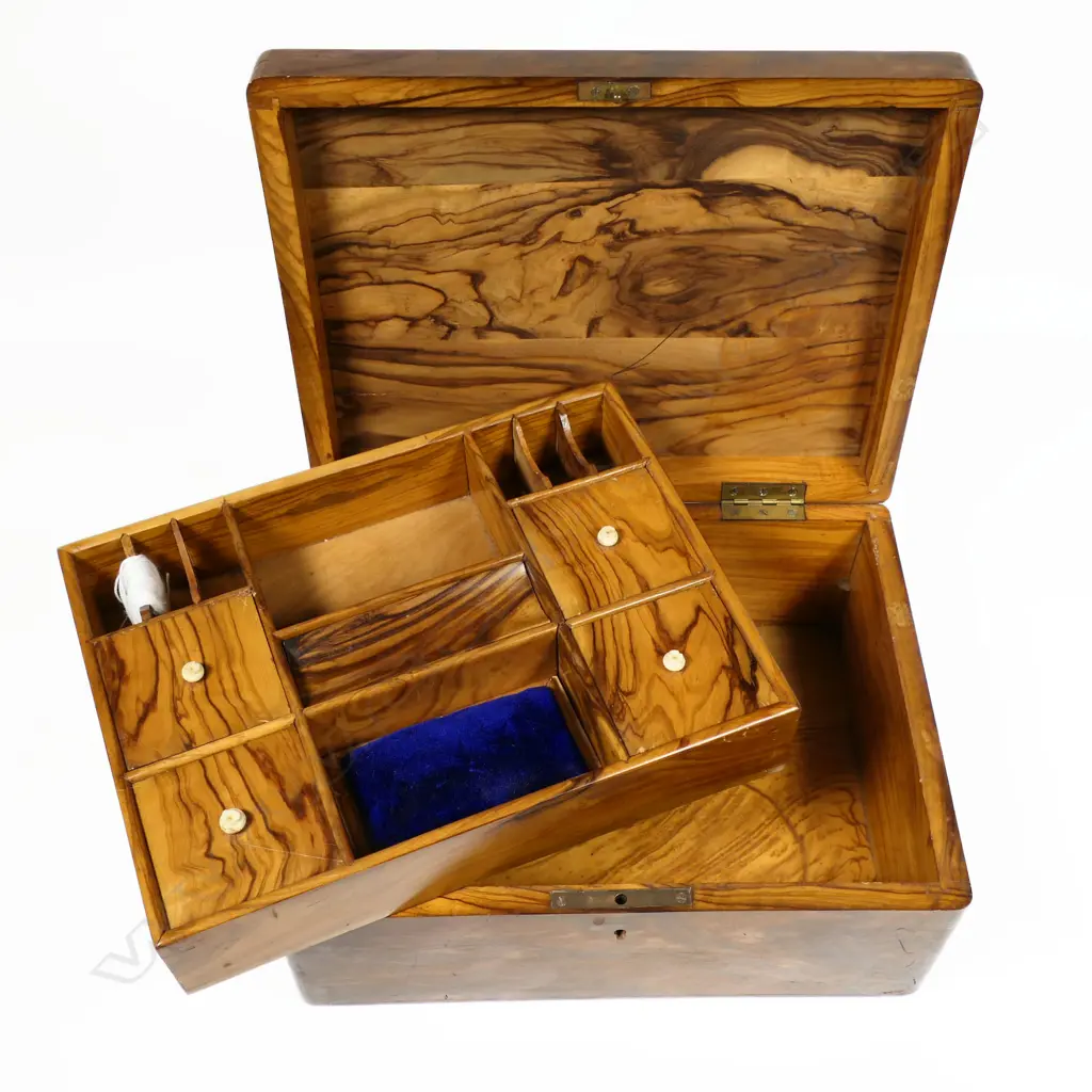 An olive wood work box, souvenir of a pilgrimage to the Middle East, oblong, undecorated except for a band of fine Tunbridge inlay framing the inked name 'Jerusalem'. Interior fitted with a lift out upper tier of small lidded compartments, silk winders and pincushion. 255 x 155 x 110mm Image 1++