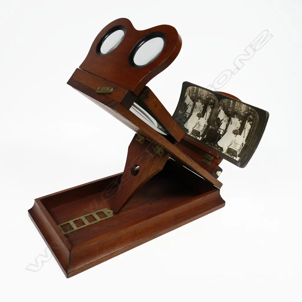 A folding tabletop magnifying stereoscopic photograph and cartes de visite viewer, mahogany case with 3¾" lens and removable binocular lenses, folds to 145 x 270 x 75mm. Image 1++