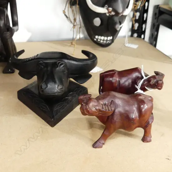 THREE CARVED BULLOCK THEMED ITEMS. TWO LIGHT BROWN FIGURES H.70mm  AND ONE EBONY BUST H. 175mm