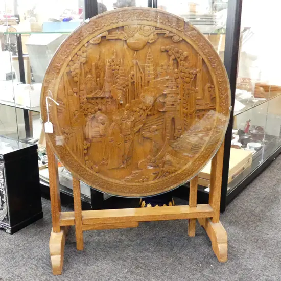 CIRCULAR FOLDING COFFEE TABLE WITH CARVED CHINESE SCENE UNDER GLASS. 605X520mm