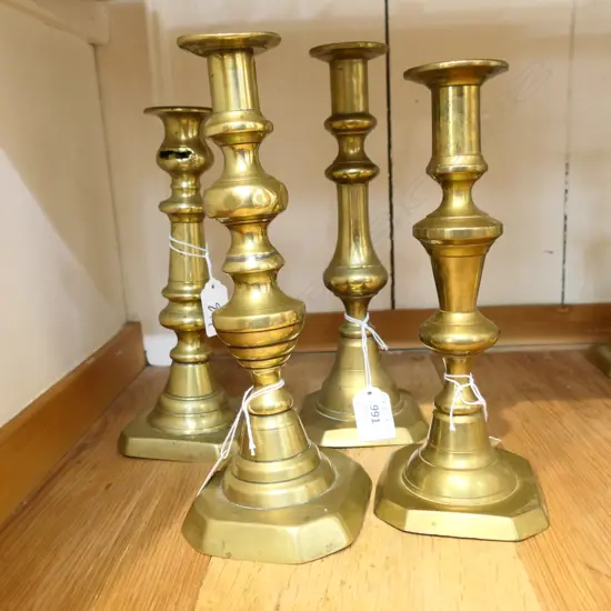 FOUR BRASS BALUSTER SHAPED OLD CANDLESTICKS. ALL APPROX 220mm HIGH.