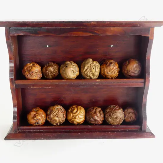 COLLECTION OF 12 ROUND CARVED WOOD NETSUKE  IN WOODEN WALL RACK 
