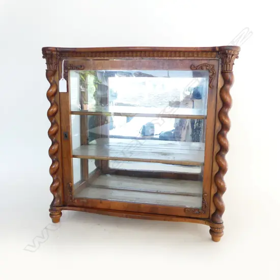 A small walnut display cabinet barley twist columns to the side with applied decoration to glazed door the interior with two painted shelves and mirror back. (some decoration absent). 500 x 225 x 485mm.