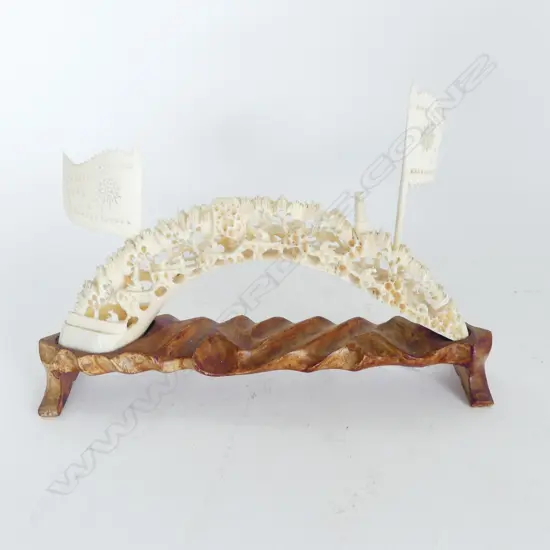 CHINESE FINELY CARVED MARINE IVORY (HIPPO TUSK) TUSK BRIDGE with flags on carved wood stand. L.250mm