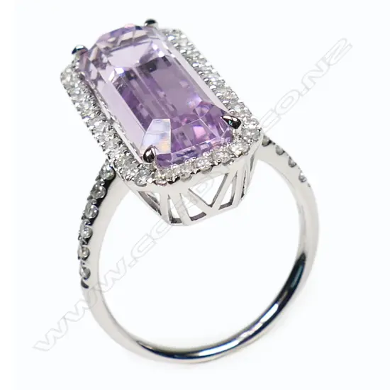 A 14ct white gold kunzite and diamond halo ring - a 9.37ct octagon cut purplish-pink kunzite (very minor eye visible inclusions), claw set and surrounded by a halo of round brilliant cut diamonds, with further diamonds set to the shoulders (Colour J-K, Clarity SI2-I2), micro claw set. TDW. 0.51ct. Ring size M½.