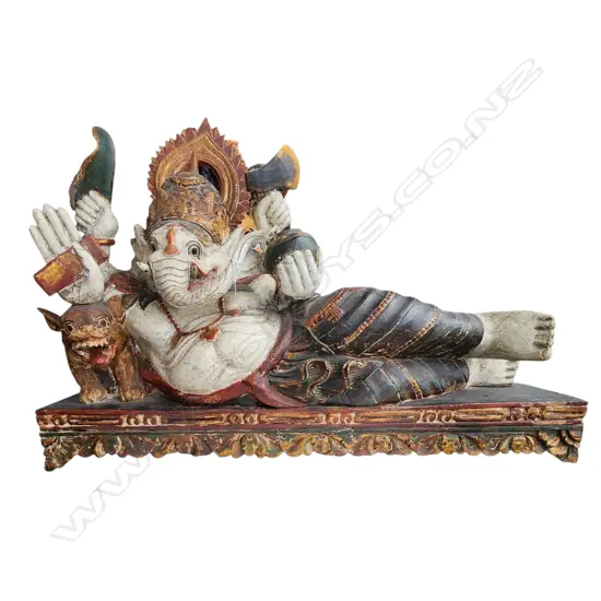 LARGE CARVED & PAINTED FIGURE of the revered deity GANESH lying upon a throne with tiger & sacred objects. L.1000mm
