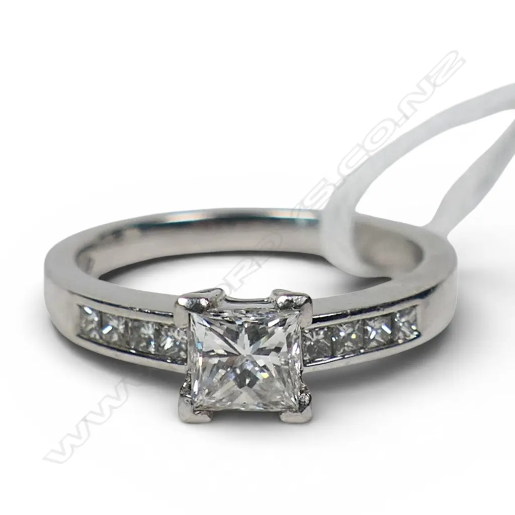 A platinum and diamond ring with a 0.50ct princess cut diamond channel set, with a further four small princess cut diamonds set to each shoulder. TDW. 0.80ct. Size M. Image 1++