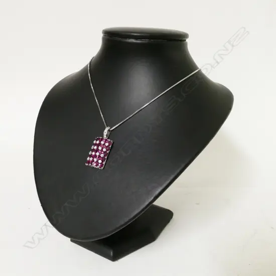 An 18ct. white gold ruby and diamond cluster pendant on chain
