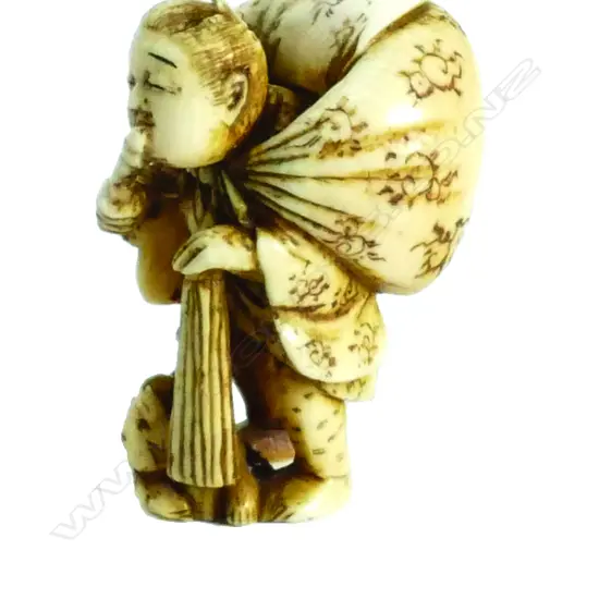 An old Japanese carved ivory netsuke of a traveller