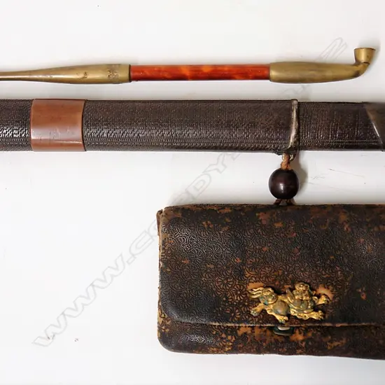 An old Japanese smoker's pipe in a container with a leather pouch and ojimi bead