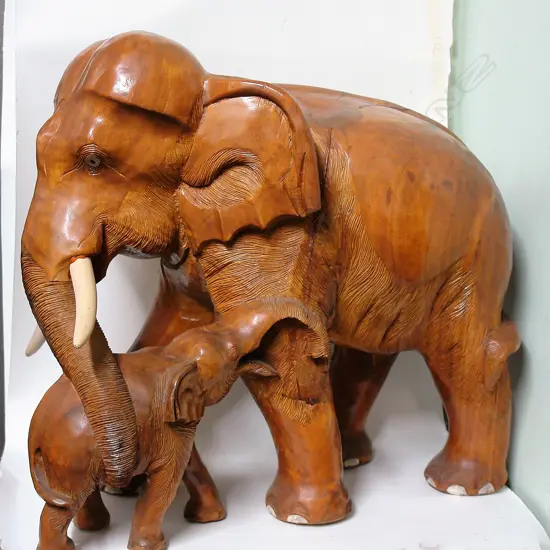 A large carved teak elephant with child