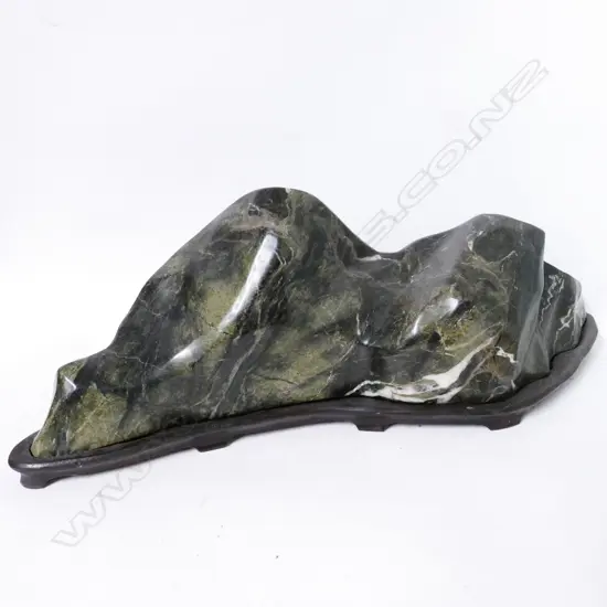 A large heavy variegated green stone mountainous boulder