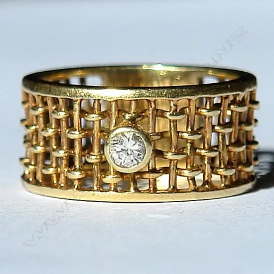 A 9ct. yellow gold wide basket weave solitaire diamond ring