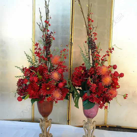A pair of imitation floral displays in decorative gilded and wooden urns
