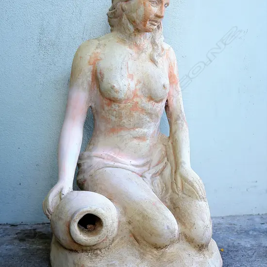 A large concrete garden sculpture of a semi-naked woman draped to her waist beside an urn