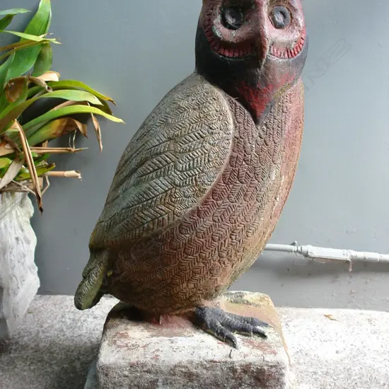 A large old concrete garden statue of an owl